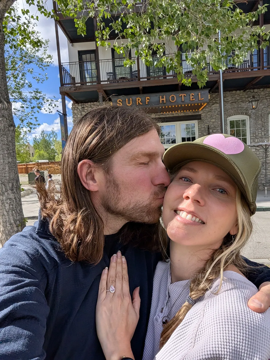 Garrett kissing Lacy on the cheek while she grins at the camera.
